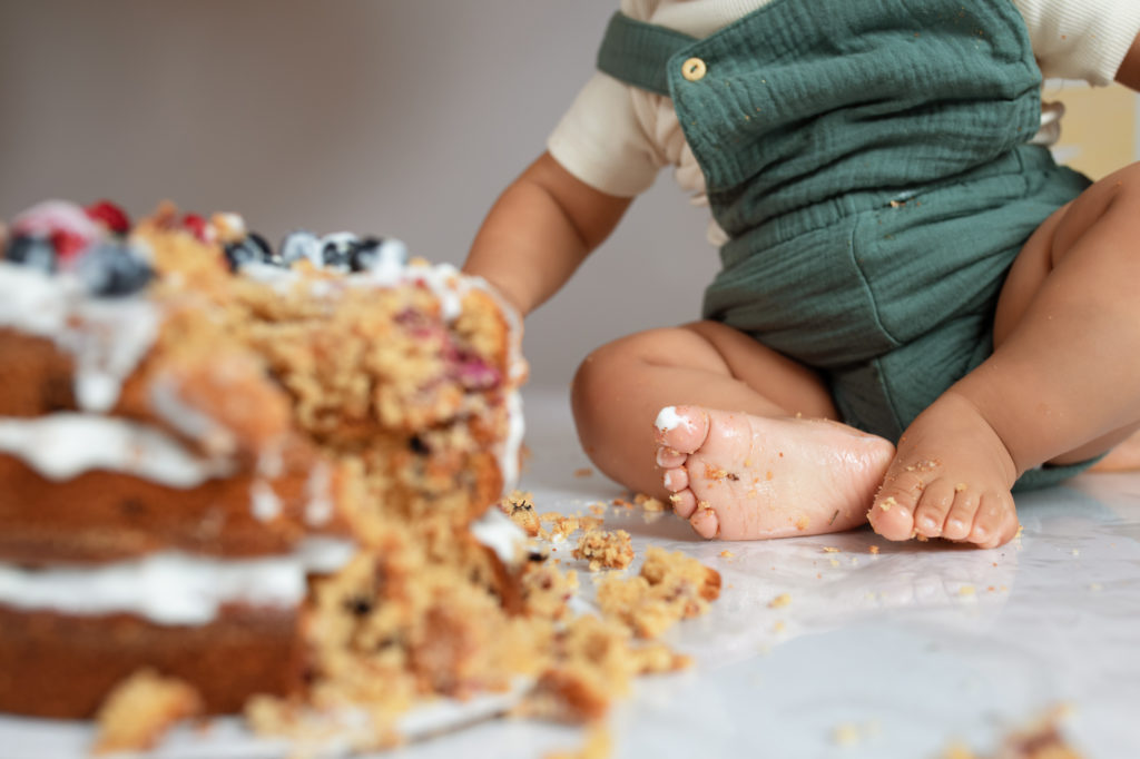 Image of baby's foot with icing and cake crumbs on it by the smashed cake