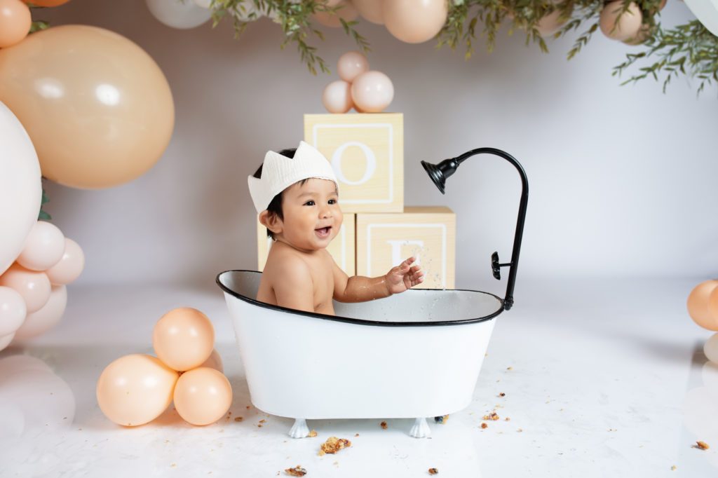 one year old baby in bath tub prop after cake smash